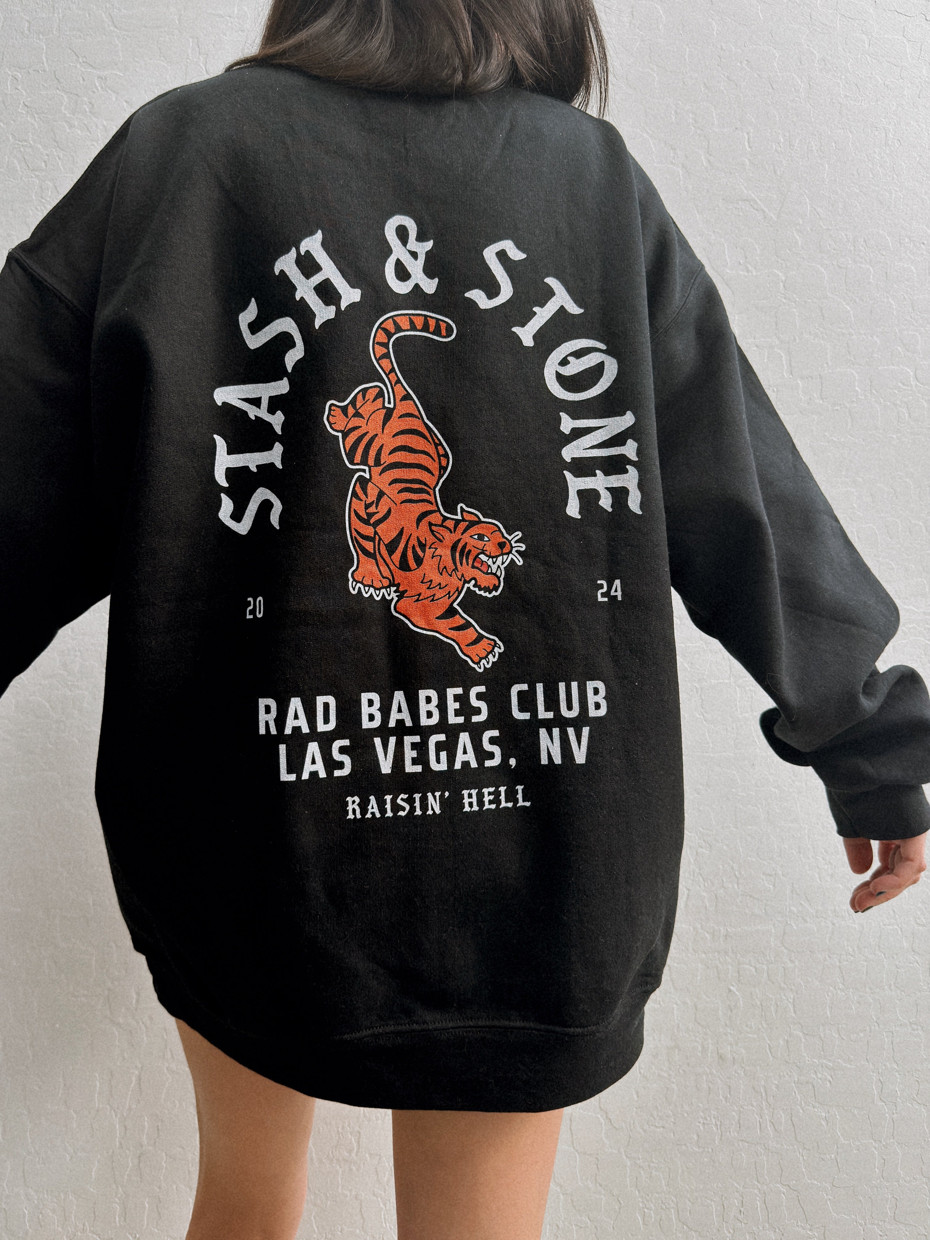 Black graphic crewneck sweatshirt with a bold design of a tiger and the words “Stash & Stone. Rad babes club, Las Vegas. Raisin’ Hell”